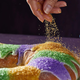 Hand sprinkling sugar onto king cake